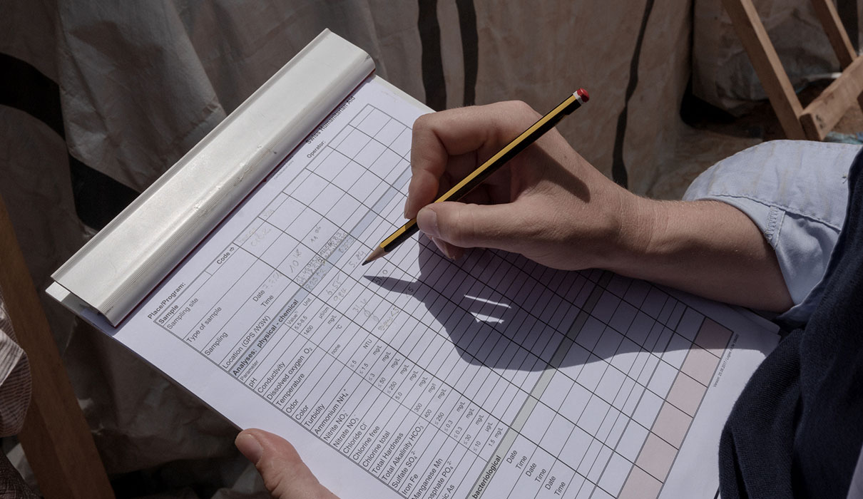 Hand holding pencil filling in sample form.